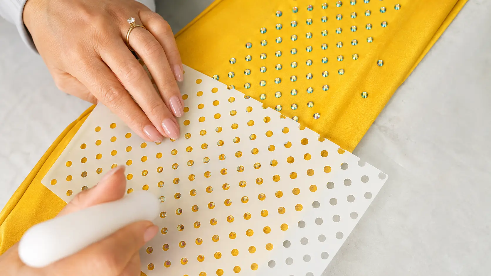 Rhinestone transfer template being applied to gold stretch costume fabric